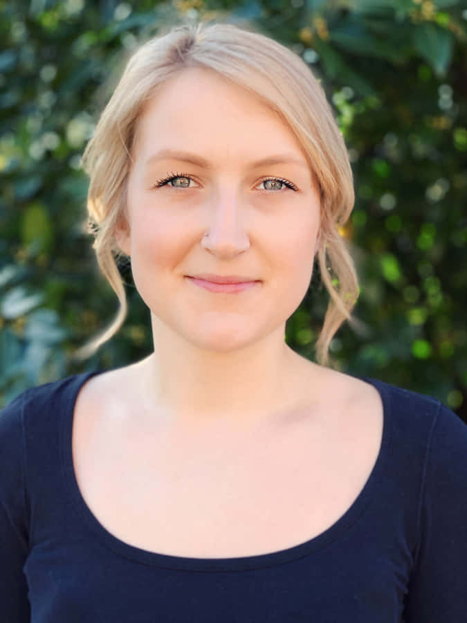 Beauty In Focus: Blurred Background Behind A Woman Posing In A Floral Dress Wallpaper