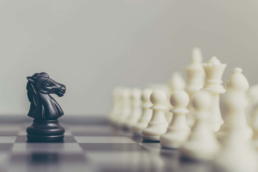 Black Knight Standing Against White Chess Pieces Wallpaper