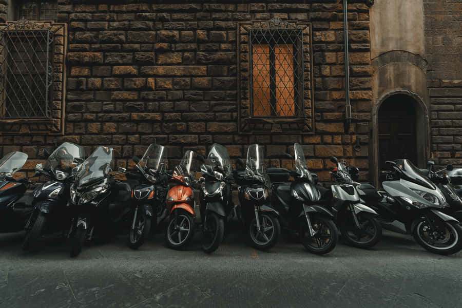 Black Motorcycles Lining Up With A Conspicuous Orange One Wallpaper