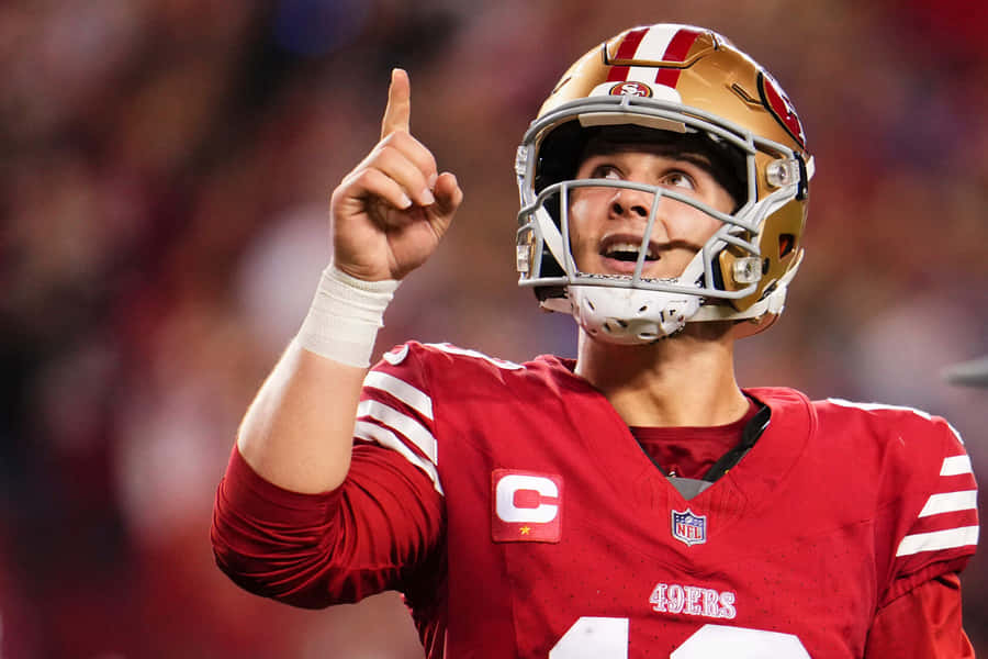 Brock Purdy49ers Quarterback Pointing Upward Wallpaper