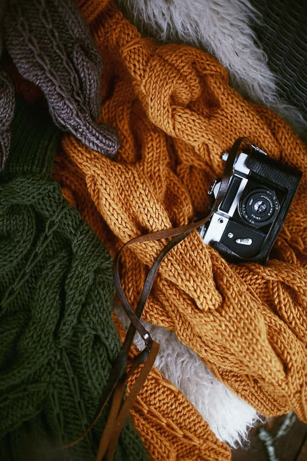 Camera On Top Of A Bronze Colored Knit Sweater Wallpaper