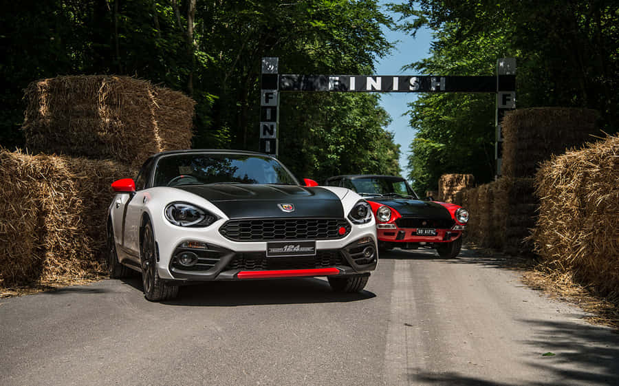 Caption: A Sleek Fiat 124 Spider In A Scenic Countryside Wallpaper