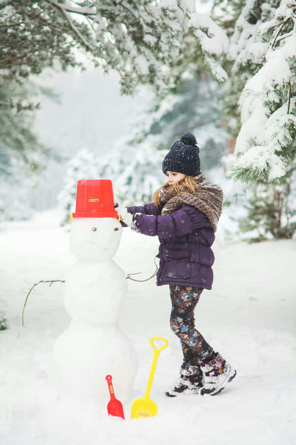 Child Building Snowman Winter Scene Wallpaper