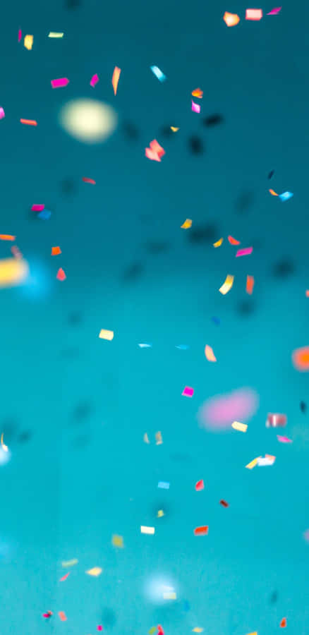 Colorful Confetti Falling Against Blue Background Wallpaper
