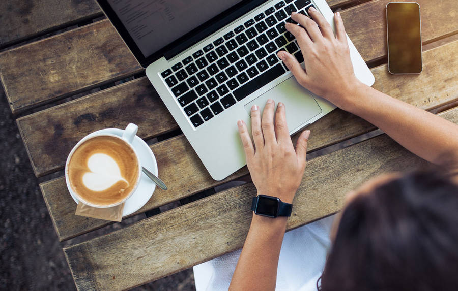 Confident Woman With Top-rated Laptop And Latte Art Coffee Wallpaper