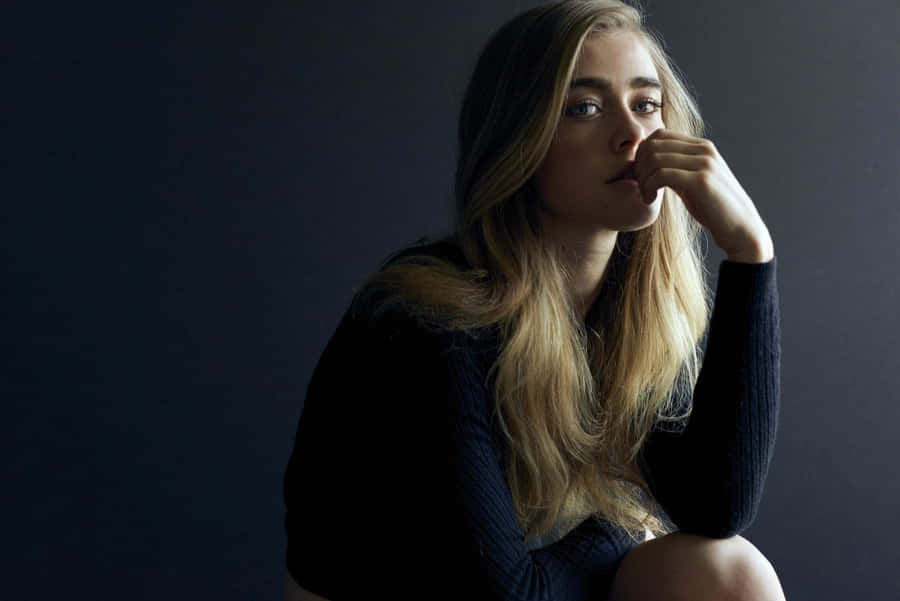 Contemplative Blonde Woman Dark Backdrop Wallpaper