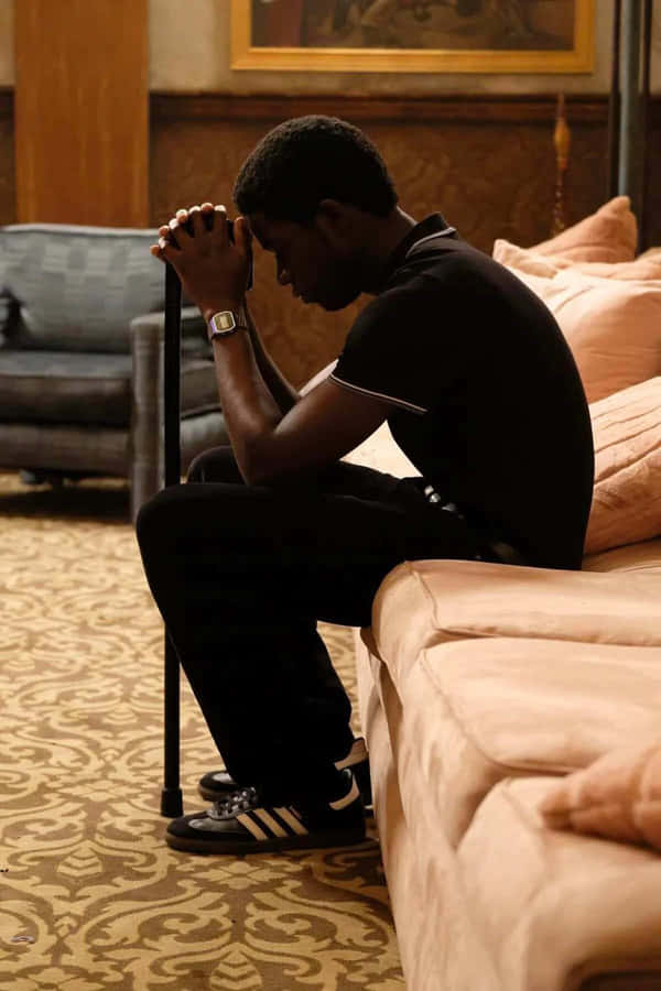 Contemplative Man Seatedon Couch Wallpaper