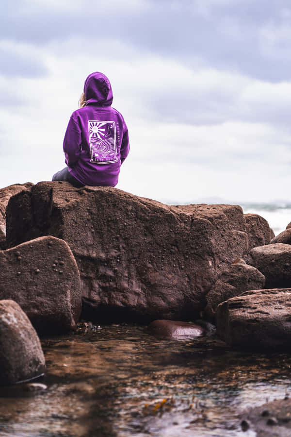 Contemplative Personin Purple Hoodieon Rocks Wallpaper