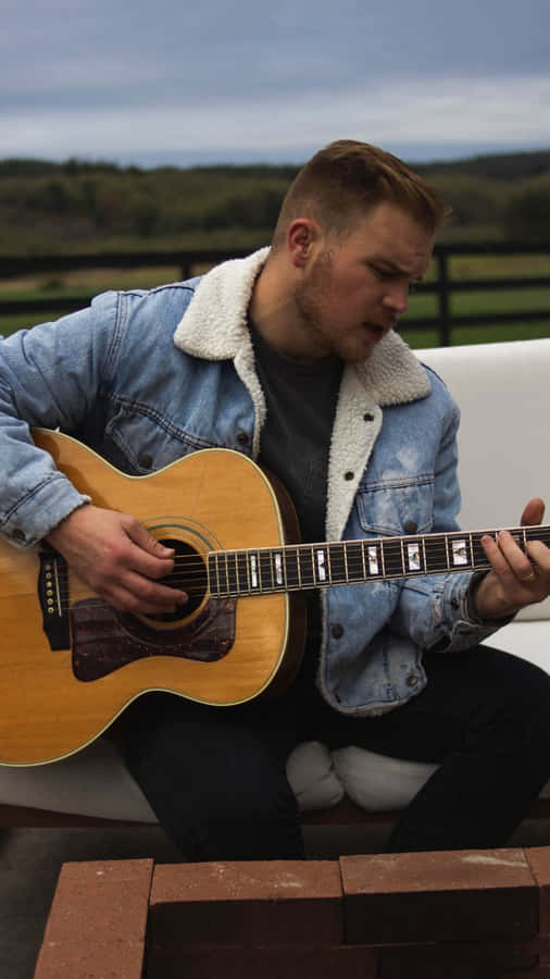 Country Musician Playing Guitar Outdoors Wallpaper