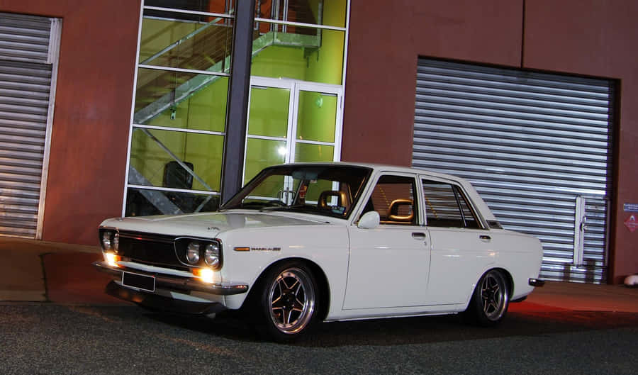 Datsun Classic Car On Open Road Wallpaper