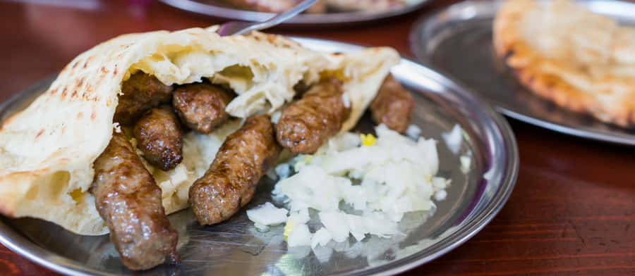 Delicious Pita Bread Stuffed With Cevapi And Fresh Onions Wallpaper