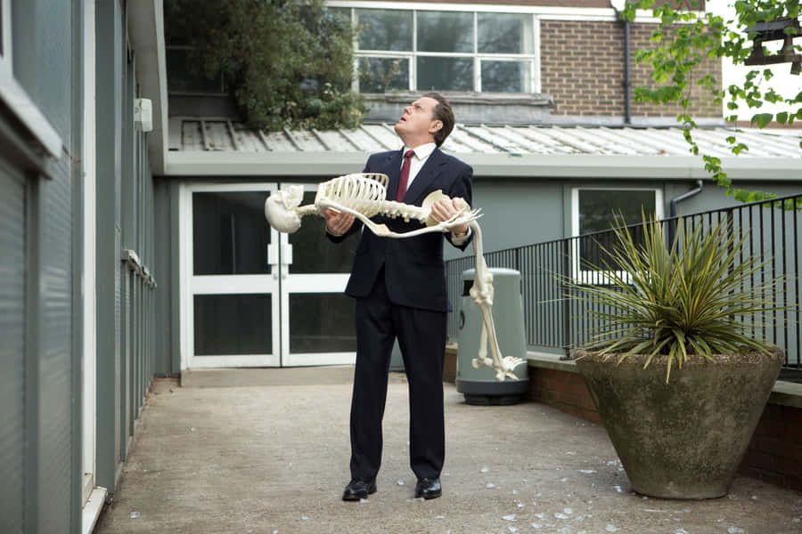 Eddie Izzard Striking A Bold Pose On Stage Wallpaper