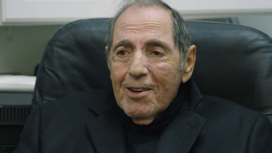 Elderly Man Smilingin Office Setting Wallpaper