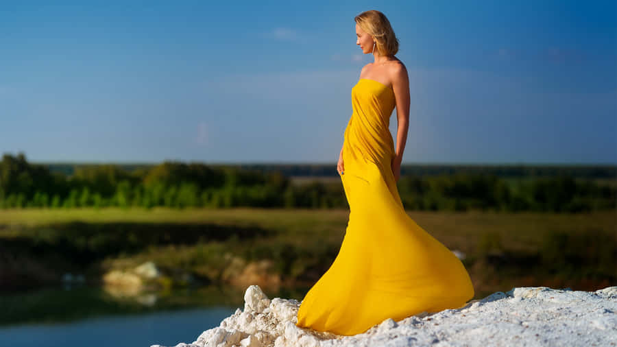 Elegant Woman In A Stylish Yellow Dress Wallpaper