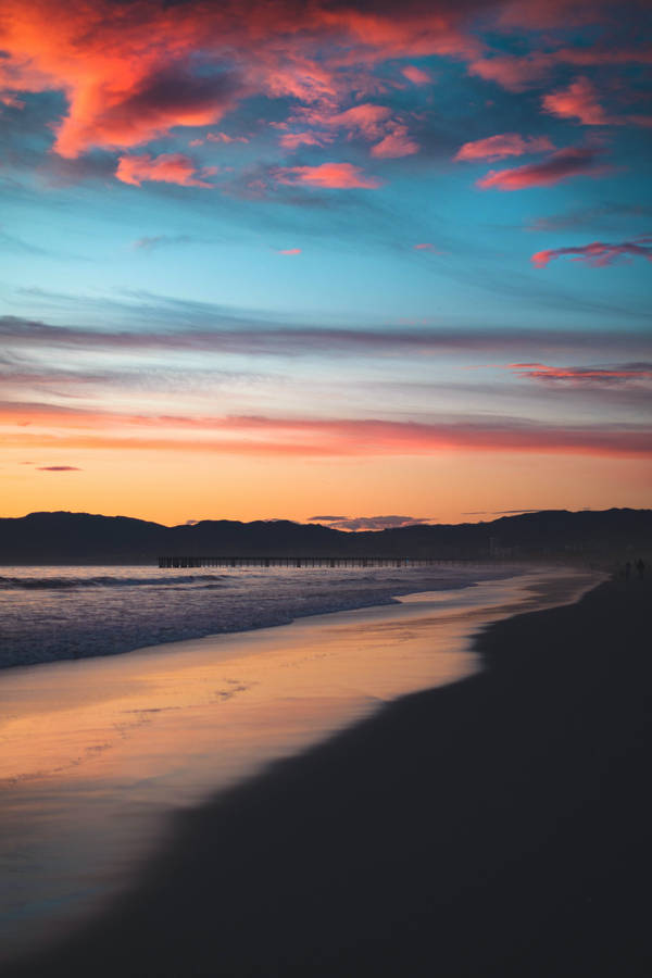 Enjoy The Vibrant Colors Of A Sunset Beach Wallpaper