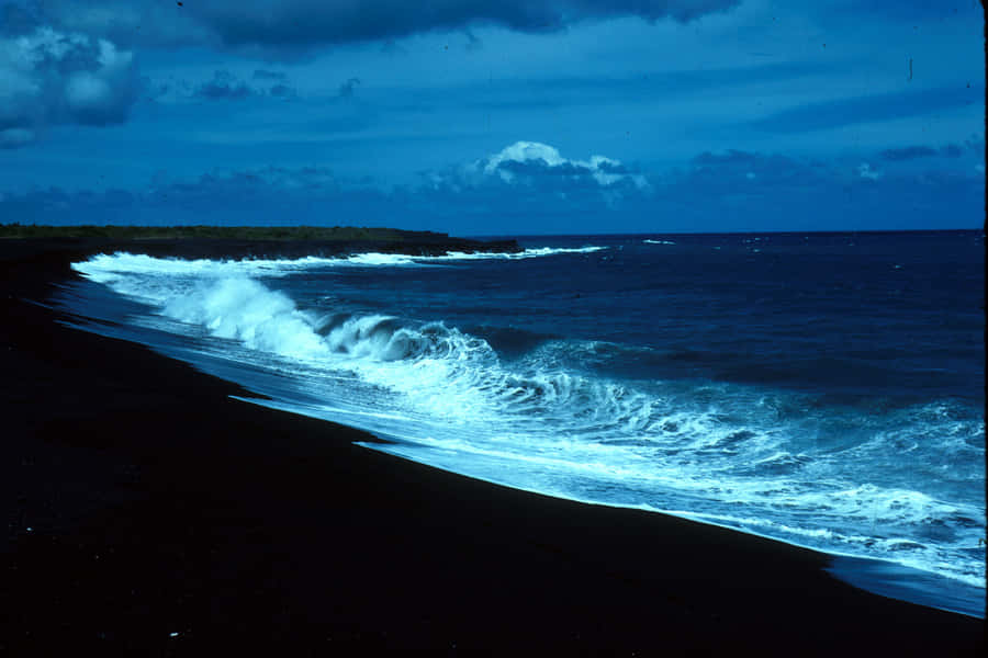 Enjoying A Peaceful Morning Stroll On The Black Sand Beach Wallpaper
