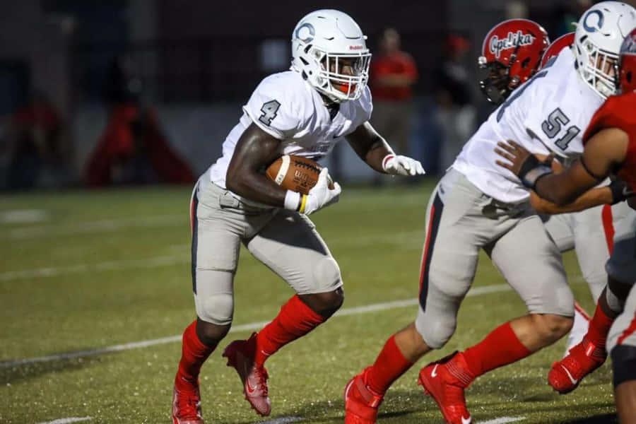 Football Player Running With Ball During Game Wallpaper