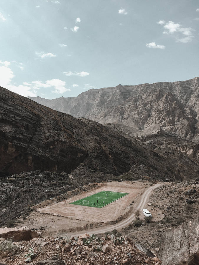 From High Atop The Mountain Range, Get A Glimpse Of A Football Stadium Below Wallpaper