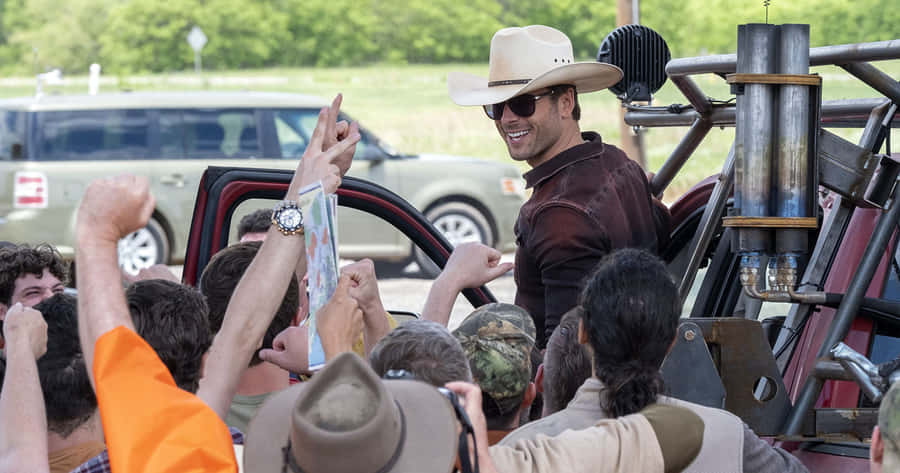 Glen Powell Cowboy Hat Fan Interaction Wallpaper