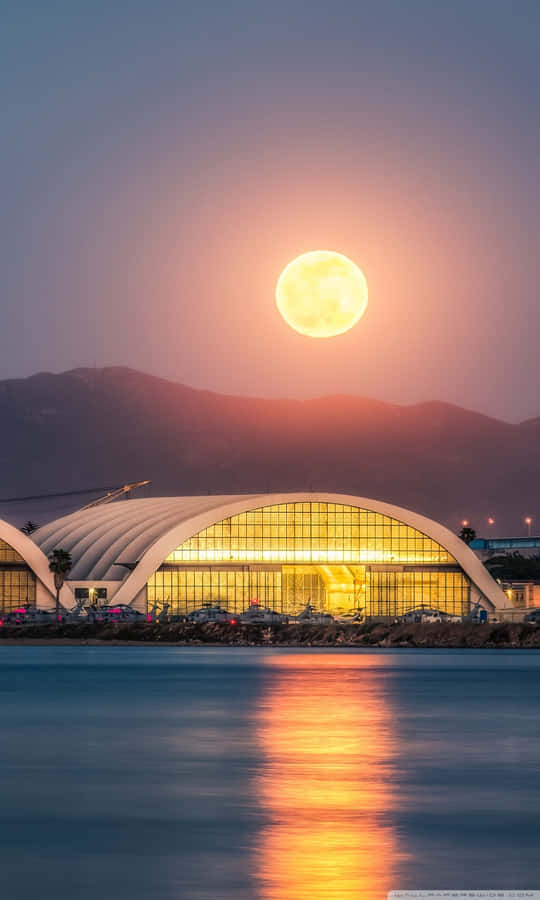 Glowing_ Moonrise_ Over_ Waterfront_ Structure.jpg Wallpaper