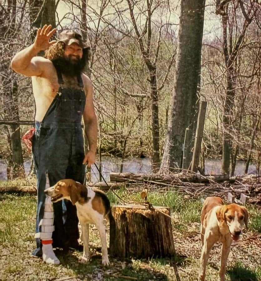 Hillbilly Jim Waving With Dogs Outdoors Wallpaper