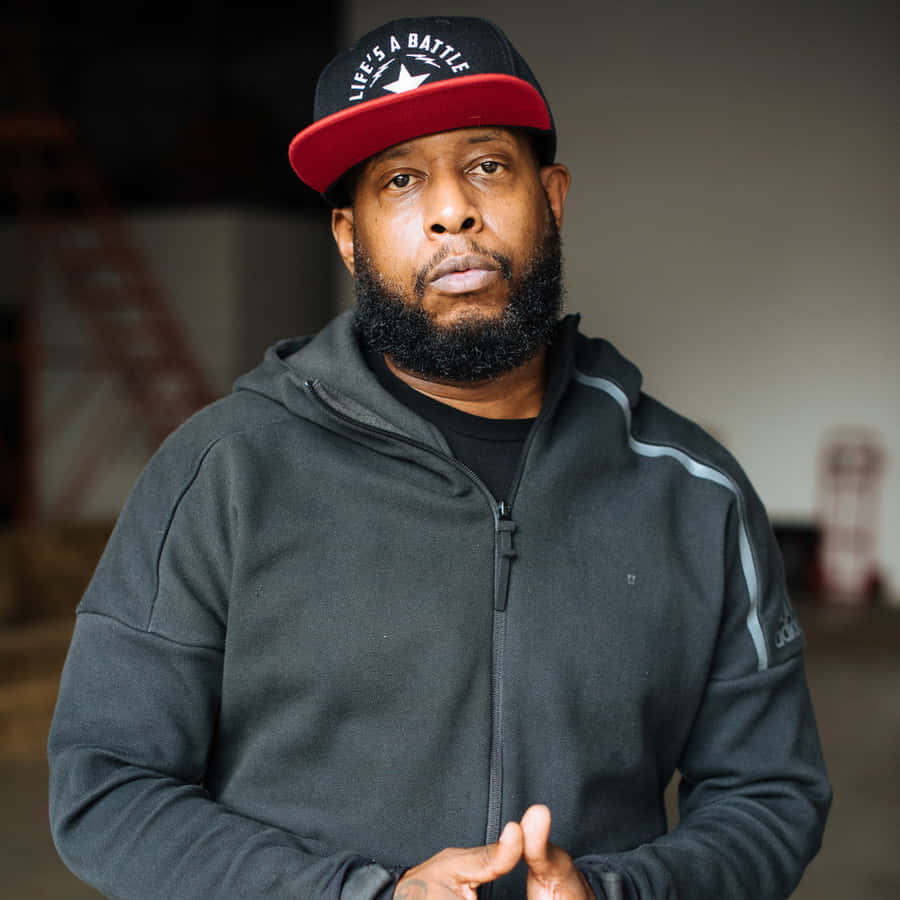 Hip Hop_ Artist_in_ Black_ Hoodie_and_ Cap Wallpaper