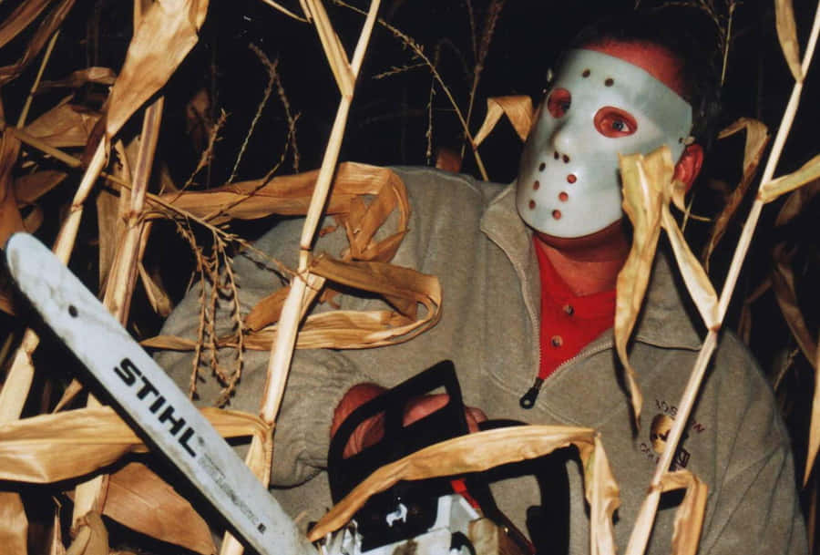 Hockey Masked Figurein Cornfieldwith Chainsaw Wallpaper
