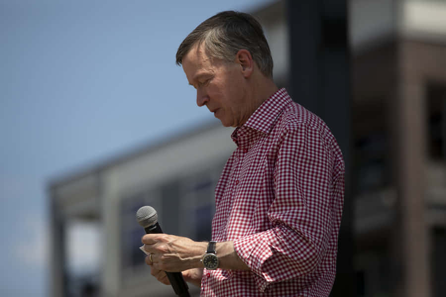 John Hickenlooper Addressing Audience With Microphone Wallpaper