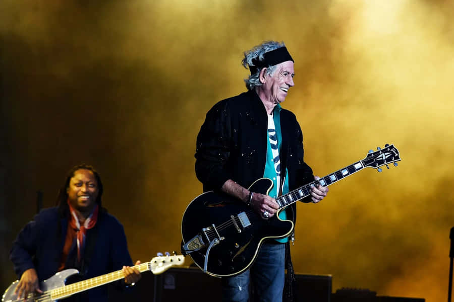 Legendary Guitarist On Stage With Bassist Wallpaper