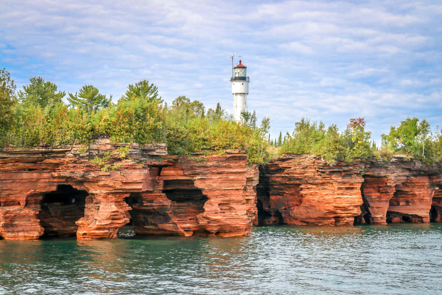 Lighthouse_ Atop_ Red_ Cliff_ Formations Wallpaper
