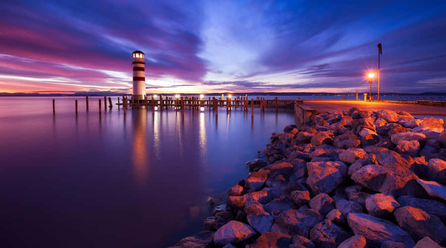 Lighthouseat Sunset Harbor Scene Wallpaper