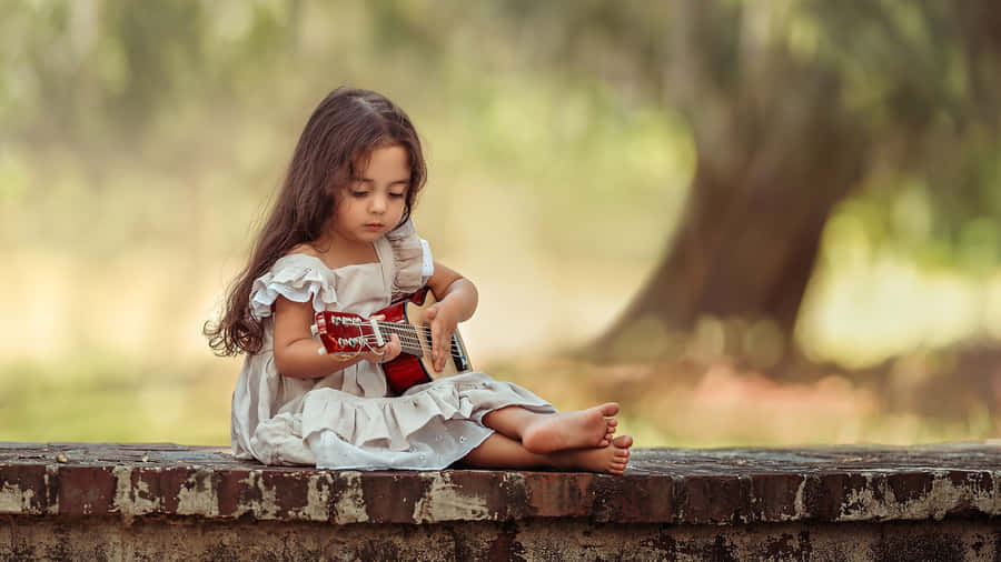 Little Girl Playing Ukulele Outdoors Wallpaper