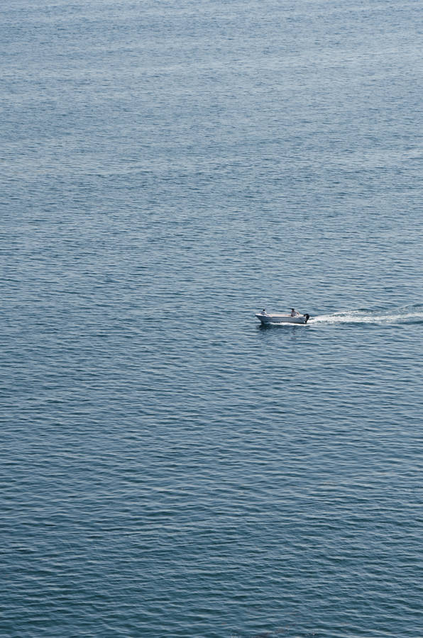 Lone Boat Sailing On The Ocean Wallpaper