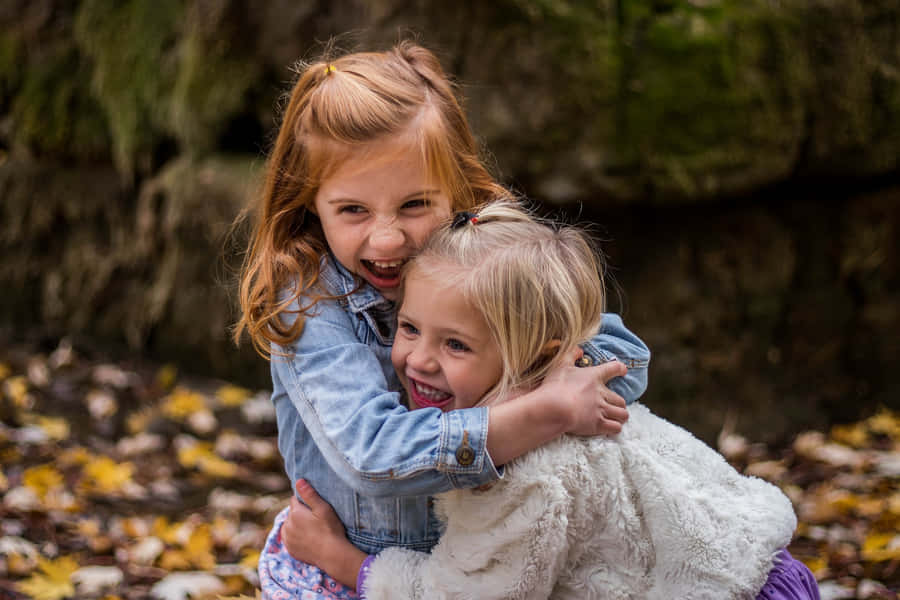 Lovely Picture Of Two Tangible Young Girls Hugging Each Other Wallpaper