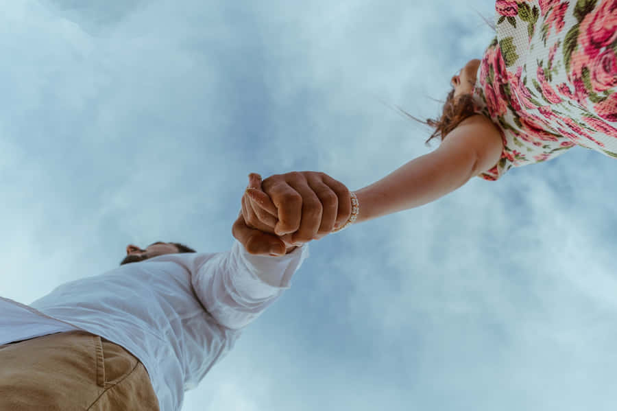 Low Angle Shot Of A Couple Holding Each Other's Tangible Hand Wallpaper