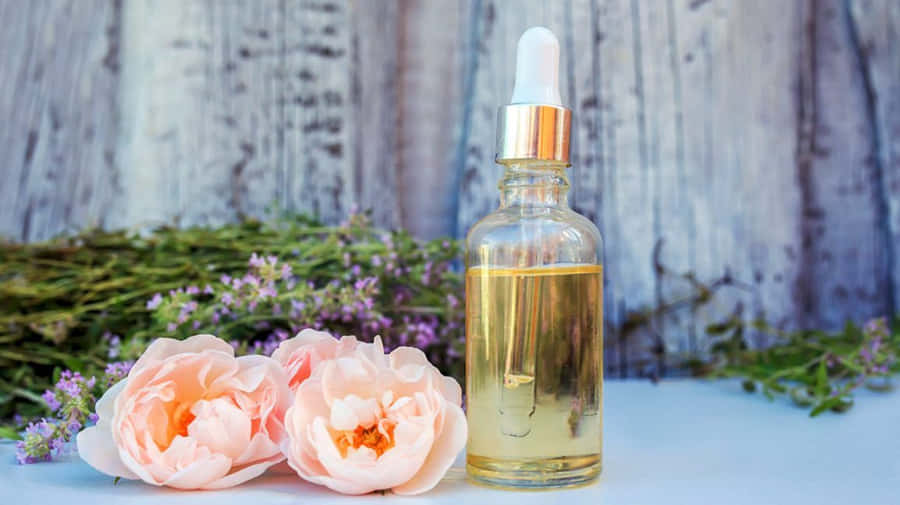 Luxurious Rose Oil In Glass Dropper Bottle With Fresh Blooming Roses Wallpaper