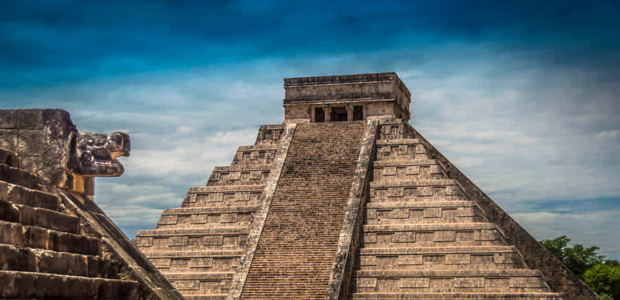 Majestic Chichen Itza Under The Cloudy Blue Sky Wallpaper