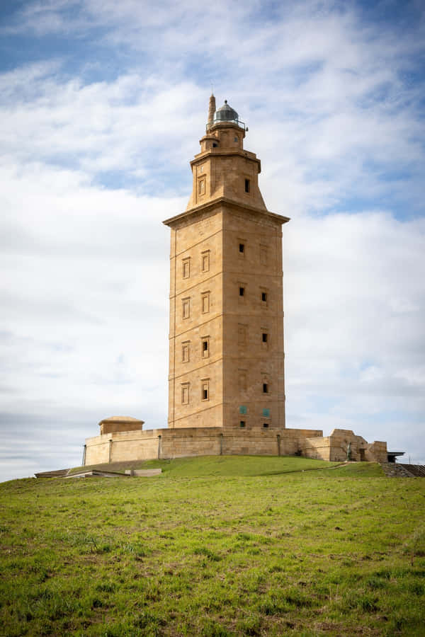 Majestic Tower Of Hercules Piercing The Blue Sky Wallpaper