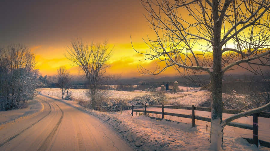 Majestic Winter Sunset Amidst A Snowy Landscape Wallpaper