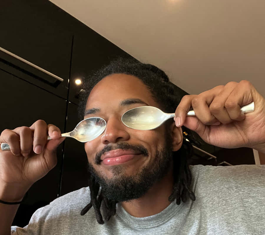 Man Holding Spoons Over Eyes Wallpaper