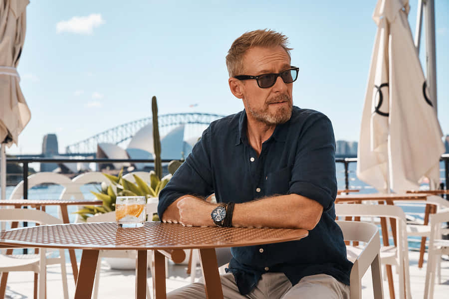 Man Relaxingat Harbourfront Cafe Wallpaper