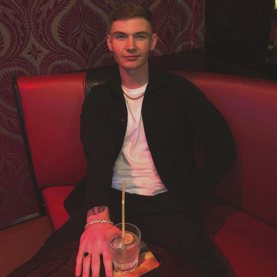 Man Seatedin Red Boothwith Drink Wallpaper