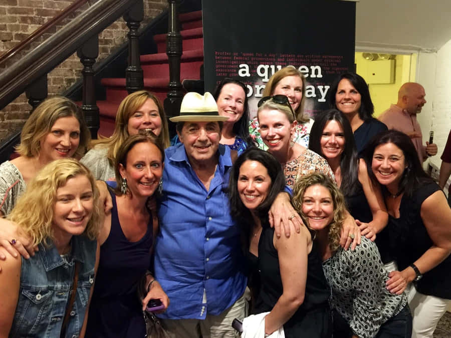 Manin Hatwith Groupof Women Smiling Wallpaper