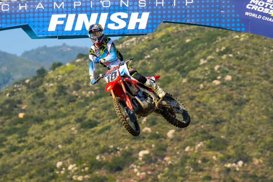 Motocross Racer Jumpsto Finish Line Wallpaper