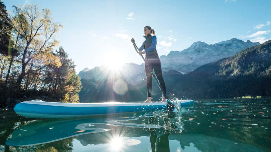Paddleboarder Gliding Across Calm Turquoise Waters On A Sunny Day Wallpaper