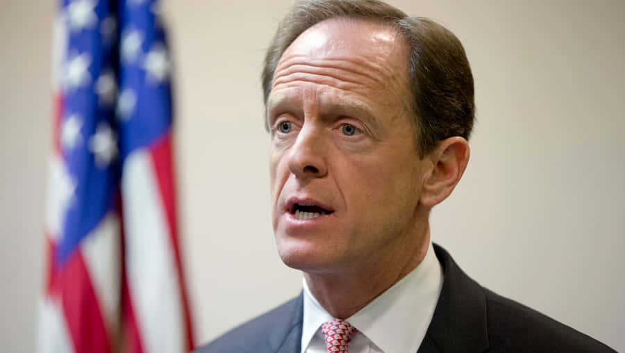 Pat Toomey Delivering A Powerful Speech Under Spotlight. Wallpaper