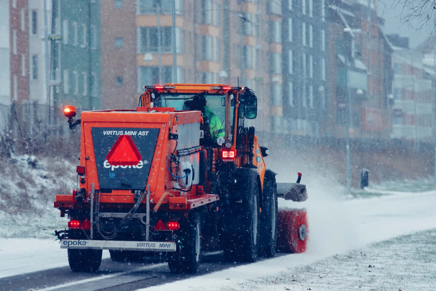 Powerful Snowplow Clearing A Road In Winter Wonderland Wallpaper