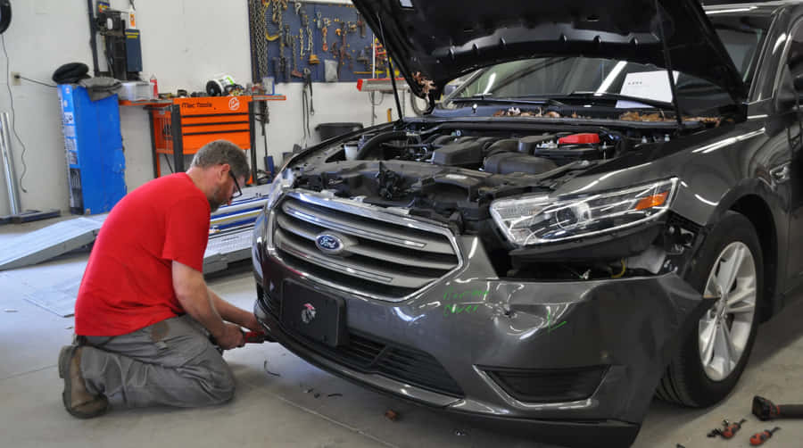 Professional Mechanic Repairing A Car In A Modern Workshop Wallpaper