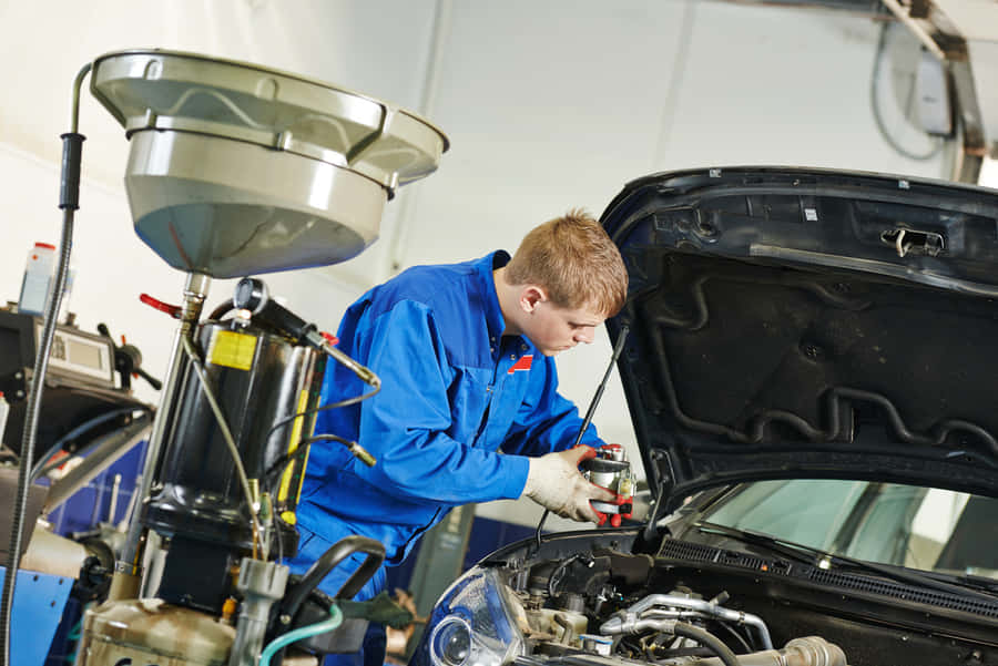 Professional Mechanic Repairing A Car In A Service Center Wallpaper