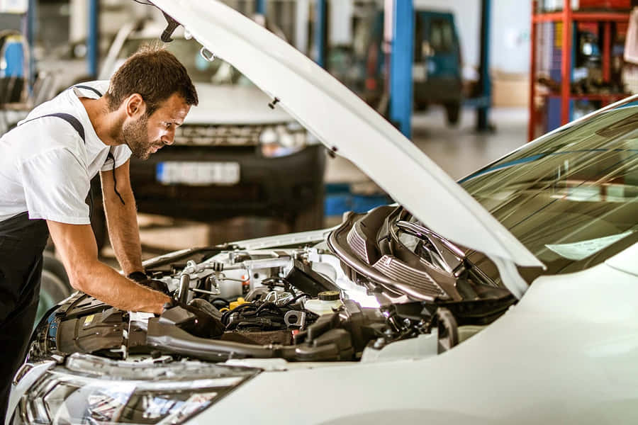 Professional Mechanic Working On A Car At Auto Repair Shop Wallpaper